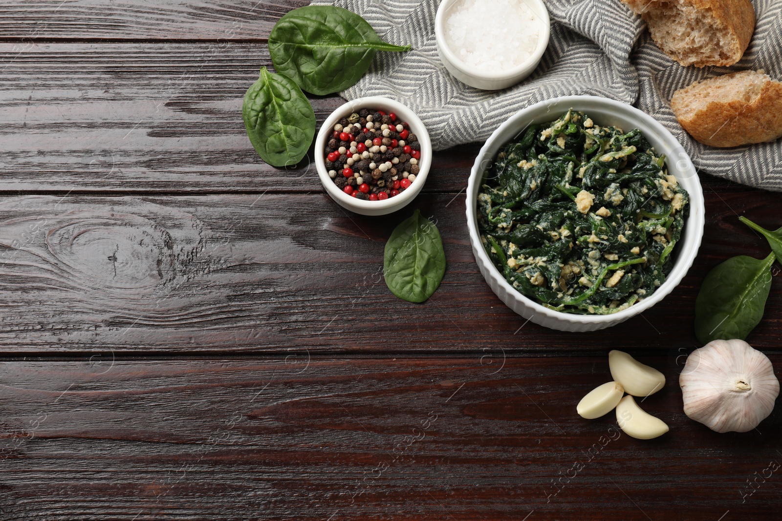 Photo of Tasty spinach dip with egg in bowl, spices and bread on wooden table, flat lay. Space for text