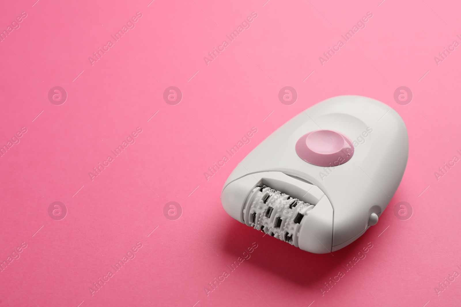 Photo of Modern epilator on pink background. Space for text