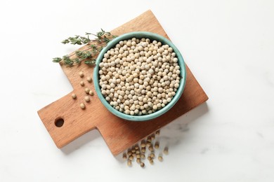 Photo of Aromatic spice. \White pepper in bowl on white marble table, top view