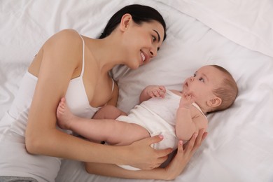 Young mother with her little baby on bed, above view