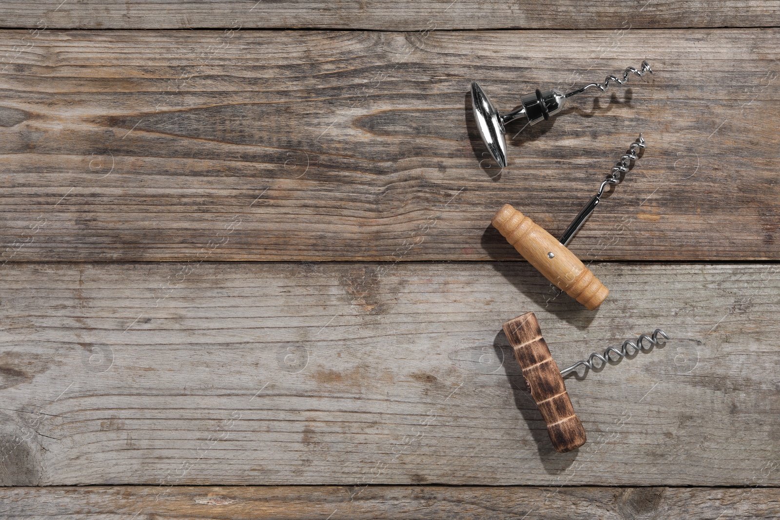 Photo of Different corkscrews on wooden table, flat lay. Space for text