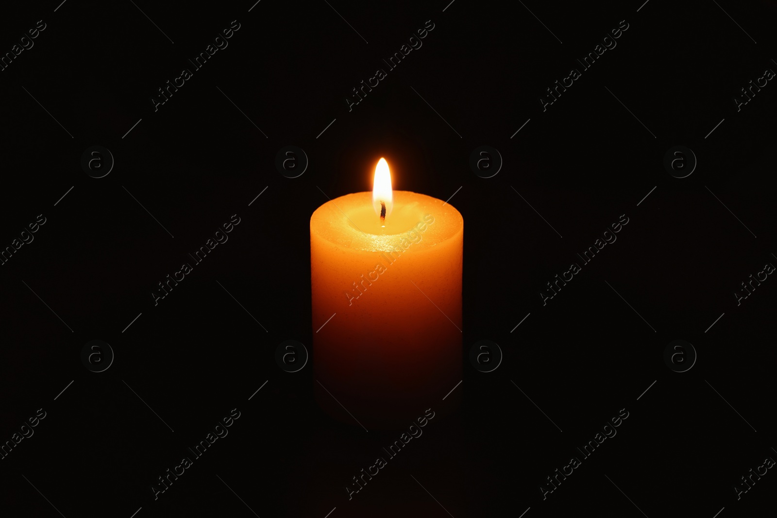 Photo of One burning wax candle on black background