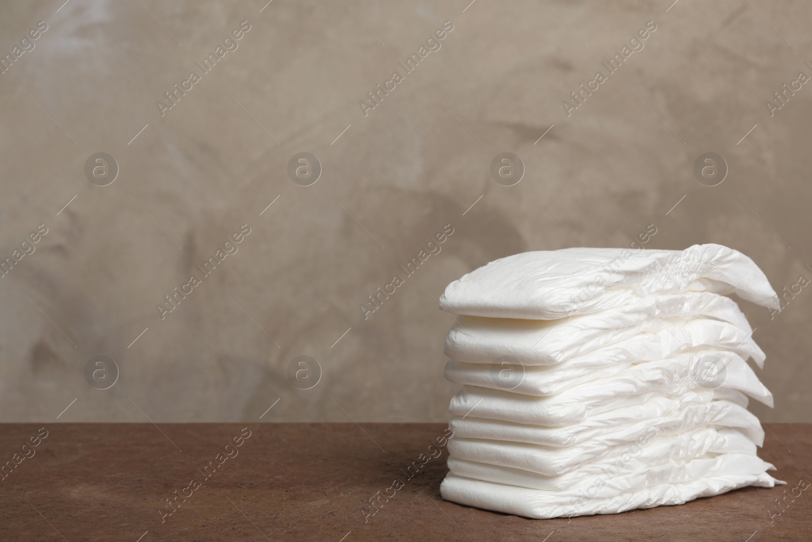 Photo of Stack of baby diapers on wooden table. Space for text