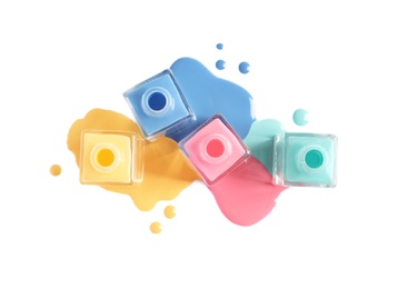 Spilled different nail polishes with bottles on white background, top view