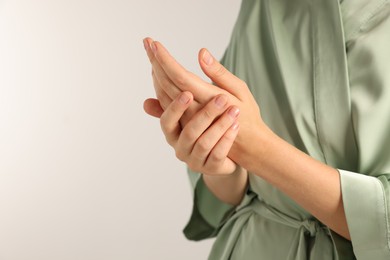 Photo of Woman applying cosmetic cream onto hand on light grey background, closeup. Space for text