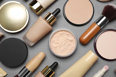 Photo of Face powders and other makeup products on grey background, flat lay
