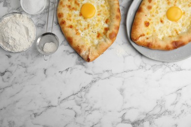 Fresh homemade khachapuri and ingredients on white marble table, flat lay. Space for text