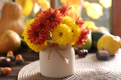 Photo of Beautiful colorful chrysanthemum flowers in vase on wooden table indoors. Autumn still life