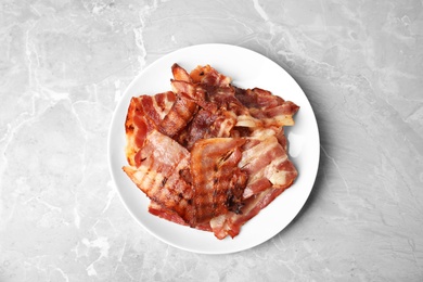 Slices of tasty fried bacon on light marble table, top view