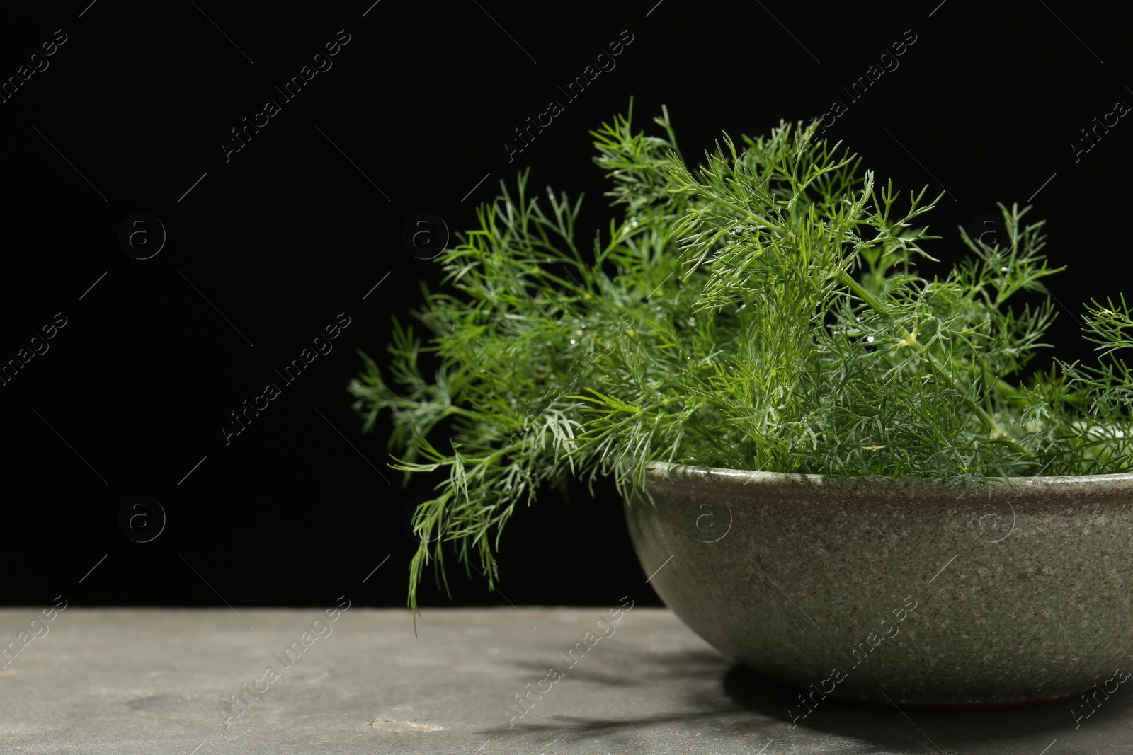 Photo of Fresh green dill in bowl on grey table, closeup. Space for text