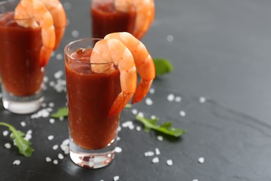 Photo of Delicious shrimp cocktail with tomato sauce served on black table, closeup. Space for text