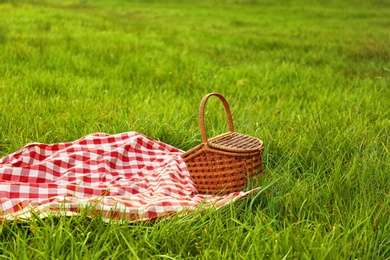 Photo of Picnic blanket and basket on grass in park