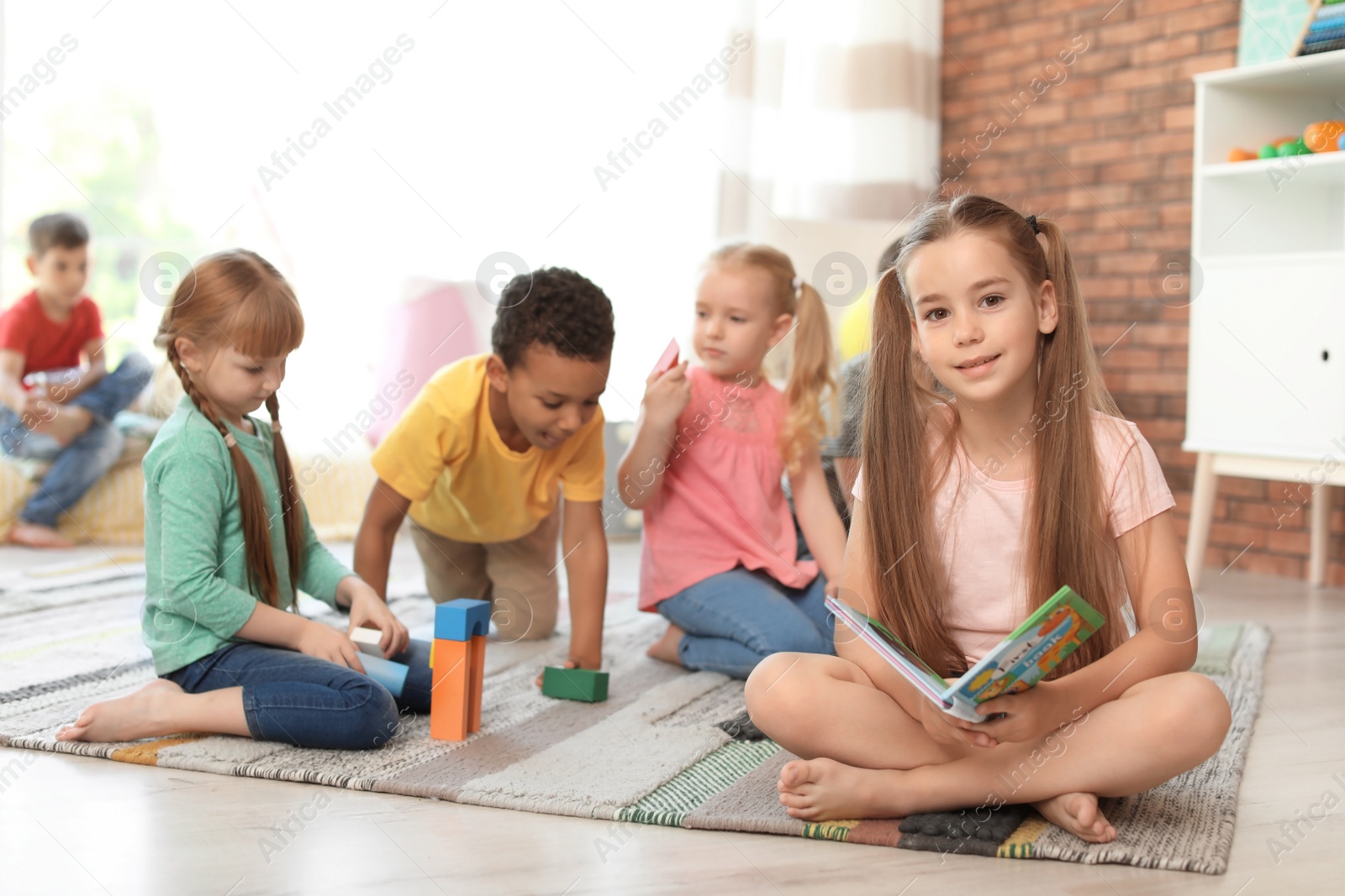 Photo of Cute little children with book and blocks indoors. Learning by playing