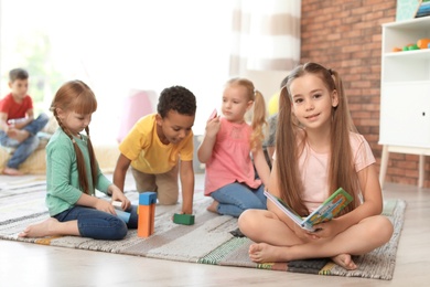 Photo of Cute little children with book and blocks indoors. Learning by playing