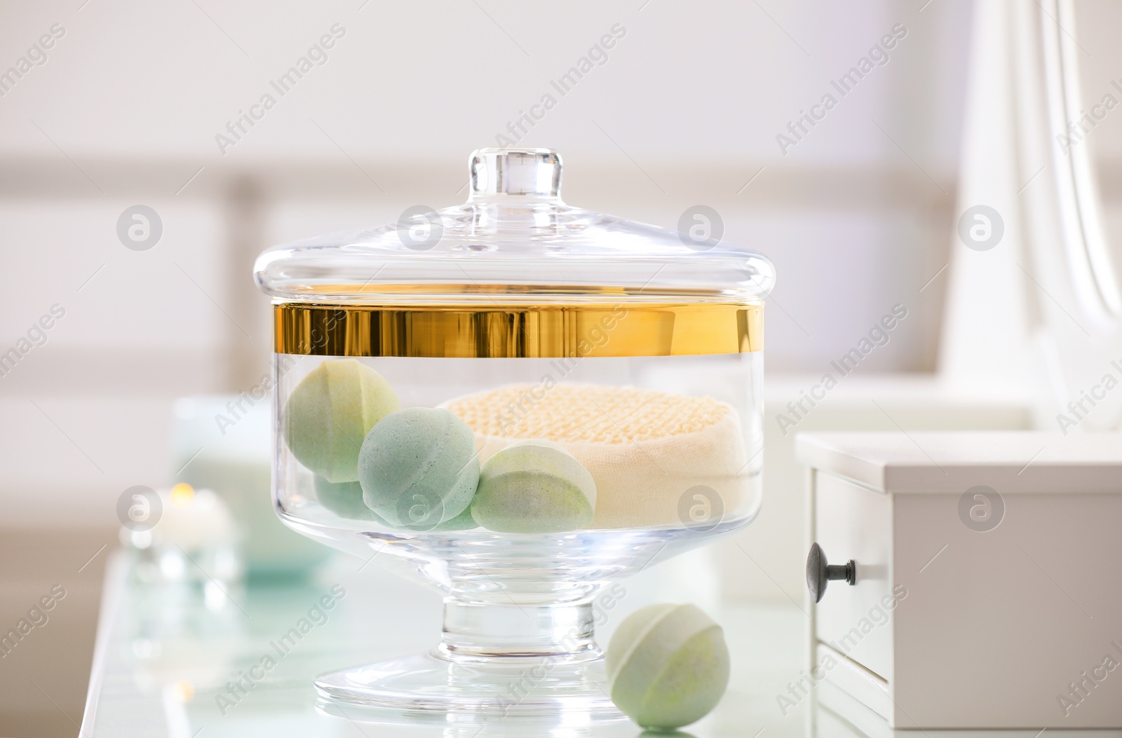 Photo of Jar with bath bombs and bath sponge on dressing table indoors