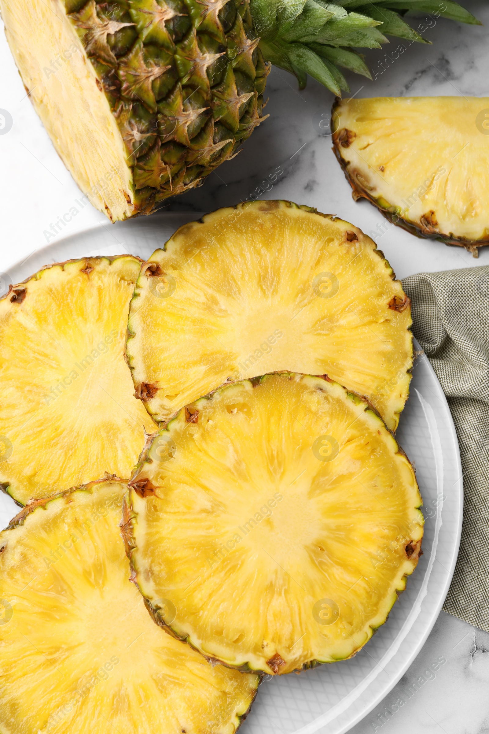 Photo of Slices of tasty ripe pineapple on white marble table, flat lay