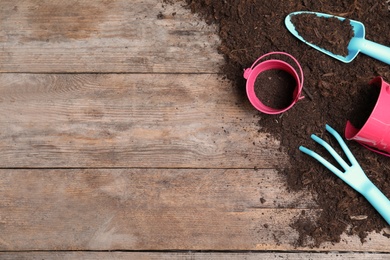 Flat lay composition with soil and gardening tools on wooden background, space for text
