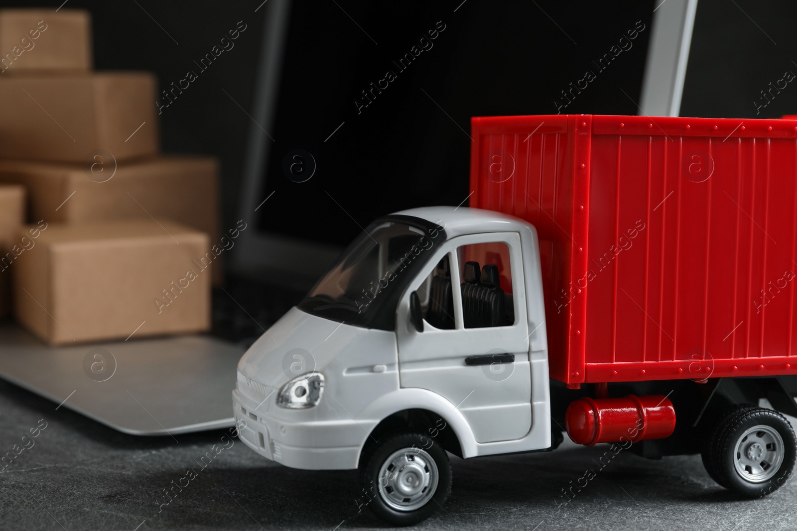 Photo of Toy truck near laptop on table. Logistics and wholesale concept