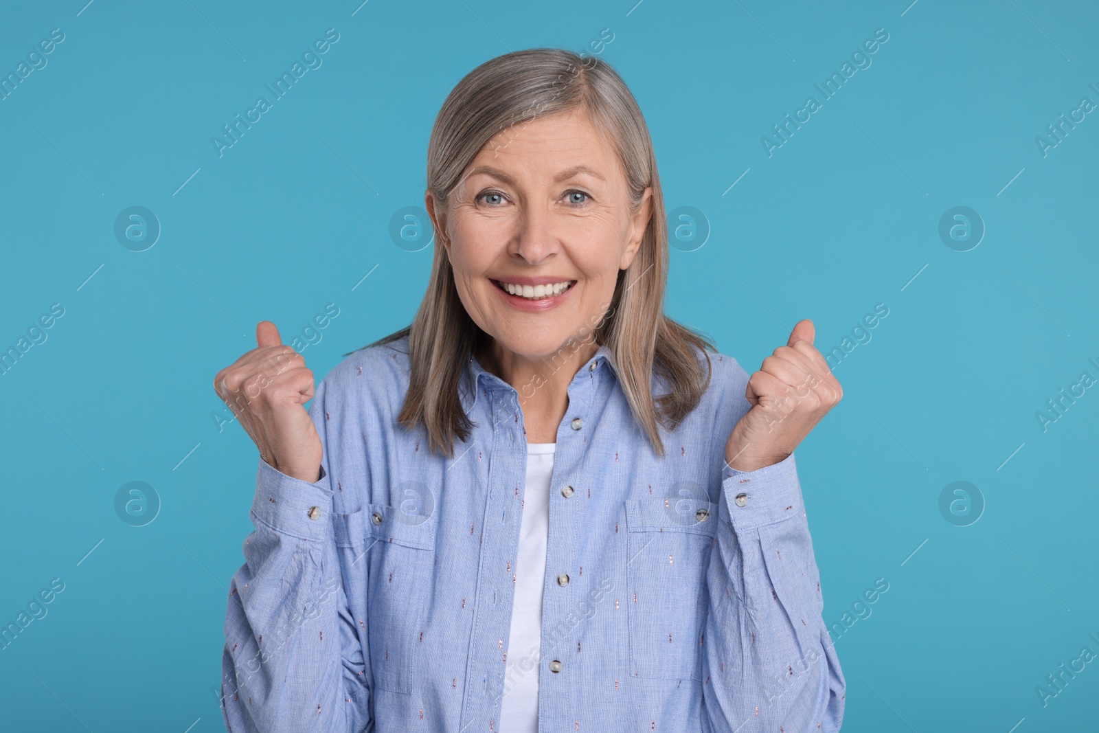 Photo of Portrait of happy surprised senior woman on light blue background