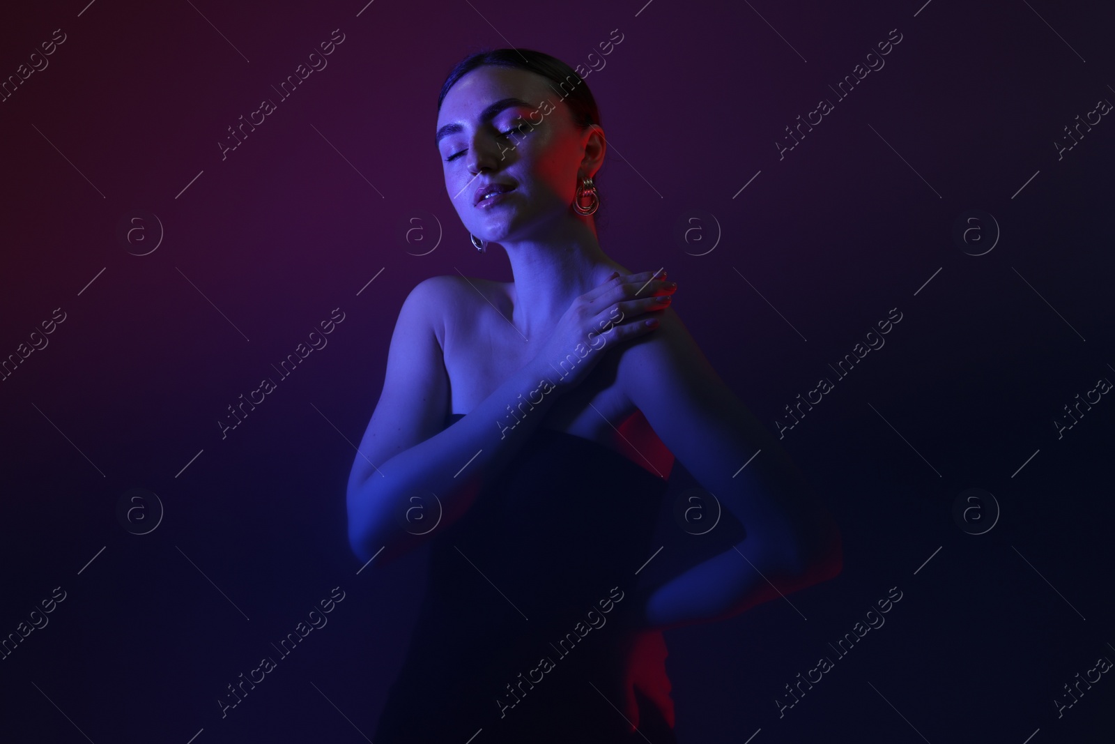 Photo of Portrait of beautiful young woman on color background in neon lights