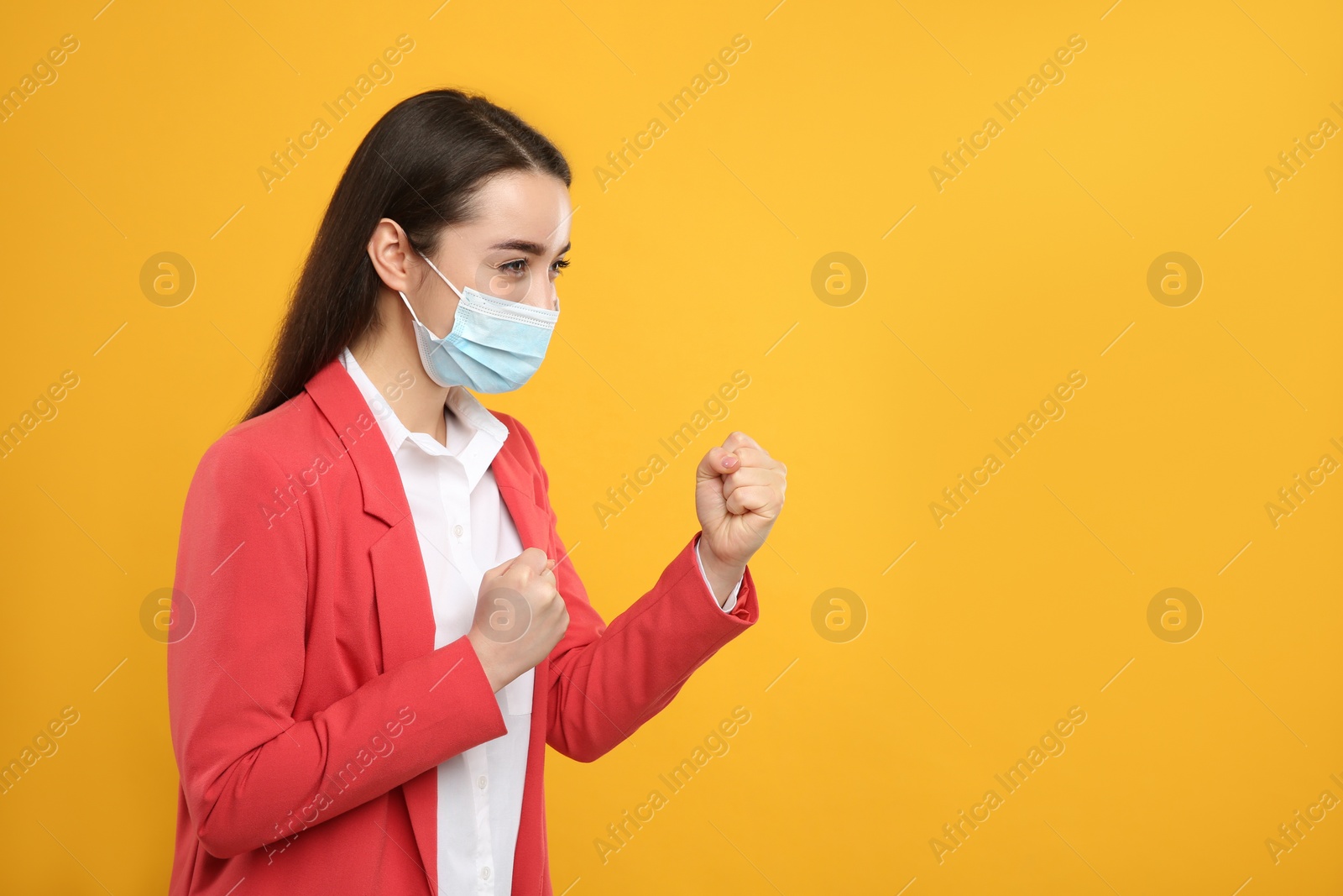 Photo of Businesswoman with protective mask in fighting pose on yellow background, space for text. Strong immunity concept