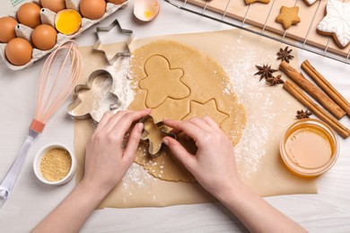 Photo of Woman making Christmas cookies with cutters at white wooden table, top view