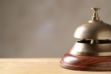 Photo of Hotel service bell on wooden table, closeup. Space for text