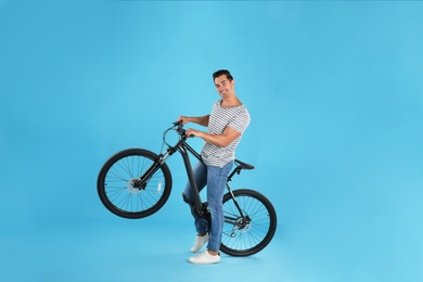 Photo of Handsome young man with modern bicycle on light blue background