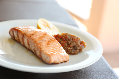 Photo of Delicious grilled salmon with garnish on plate, closeup