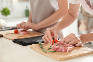 Photo of Female chef preparing meat on wooden board at table, closeup