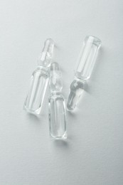 Glass ampoules with liquid on white background, top view