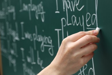 English teacher writing with chalk on green chalkboard, closeup