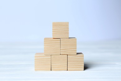 Pyramid of cubes on wooden background, space for text. Idea concept