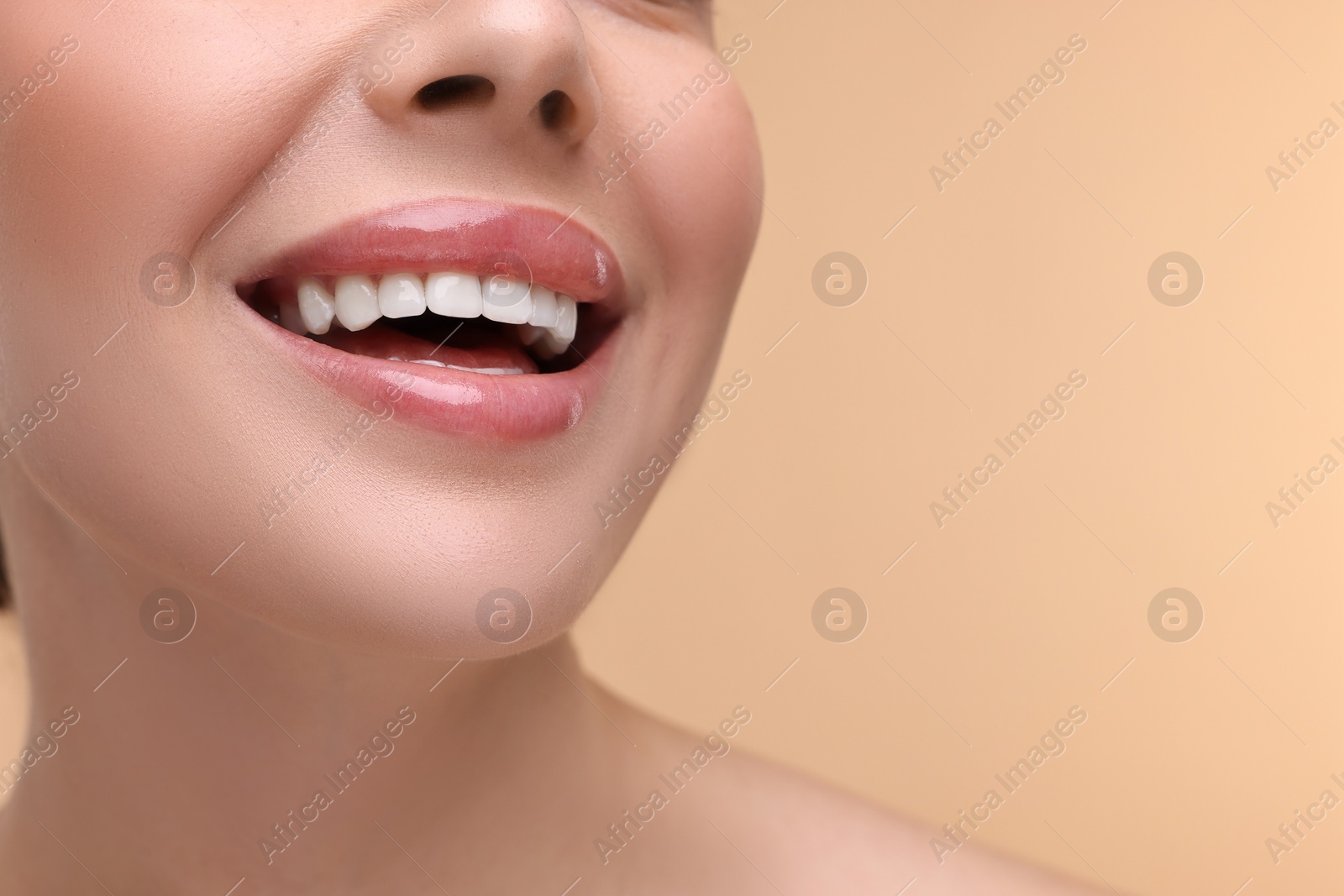 Photo of Woman with beautiful lips smiling on beige background, closeup. Space for text