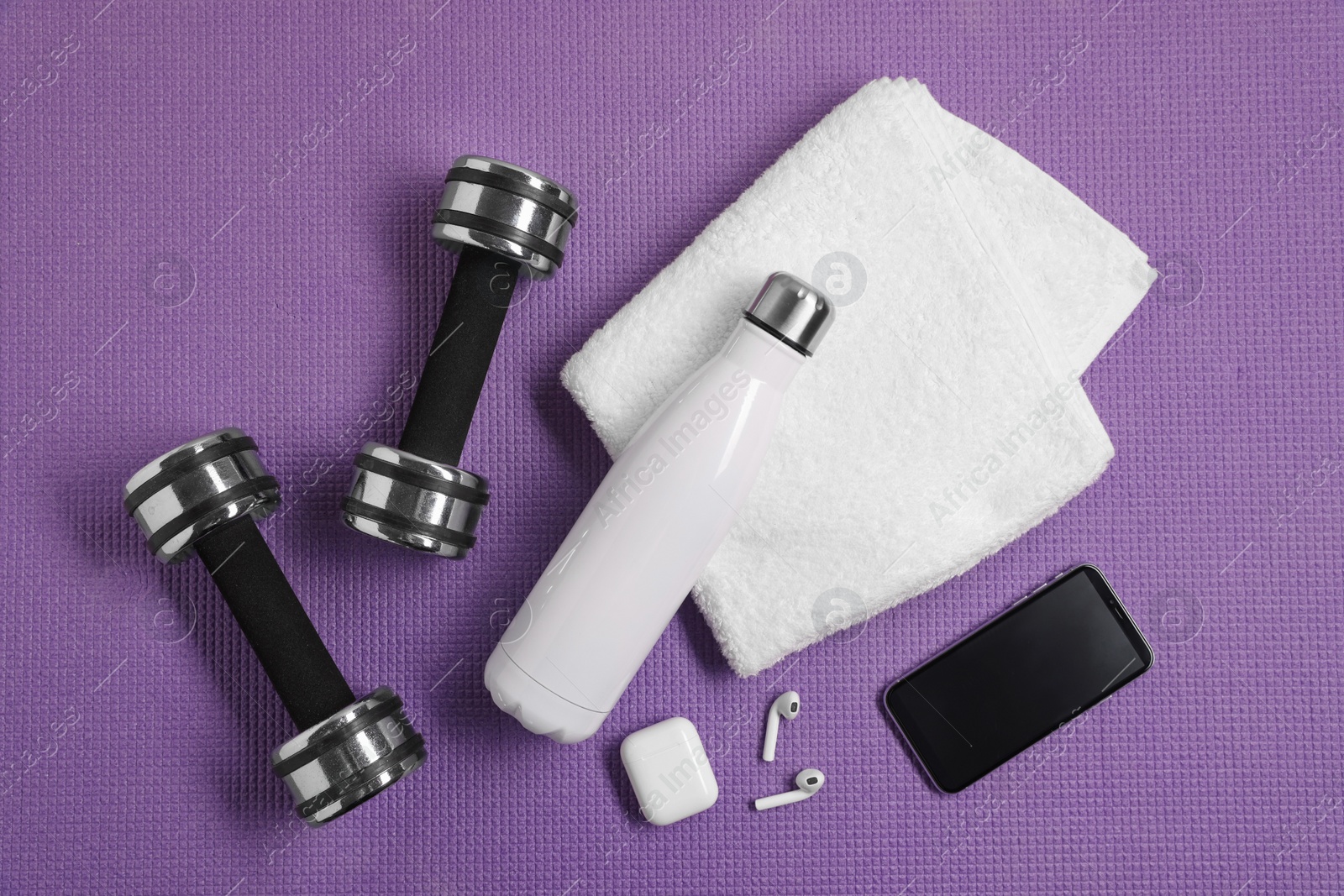 Photo of Flat lay composition with stylish thermo bottle and dumbbells on purple textured background