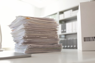 Stack of documents and folder with papers on table in office