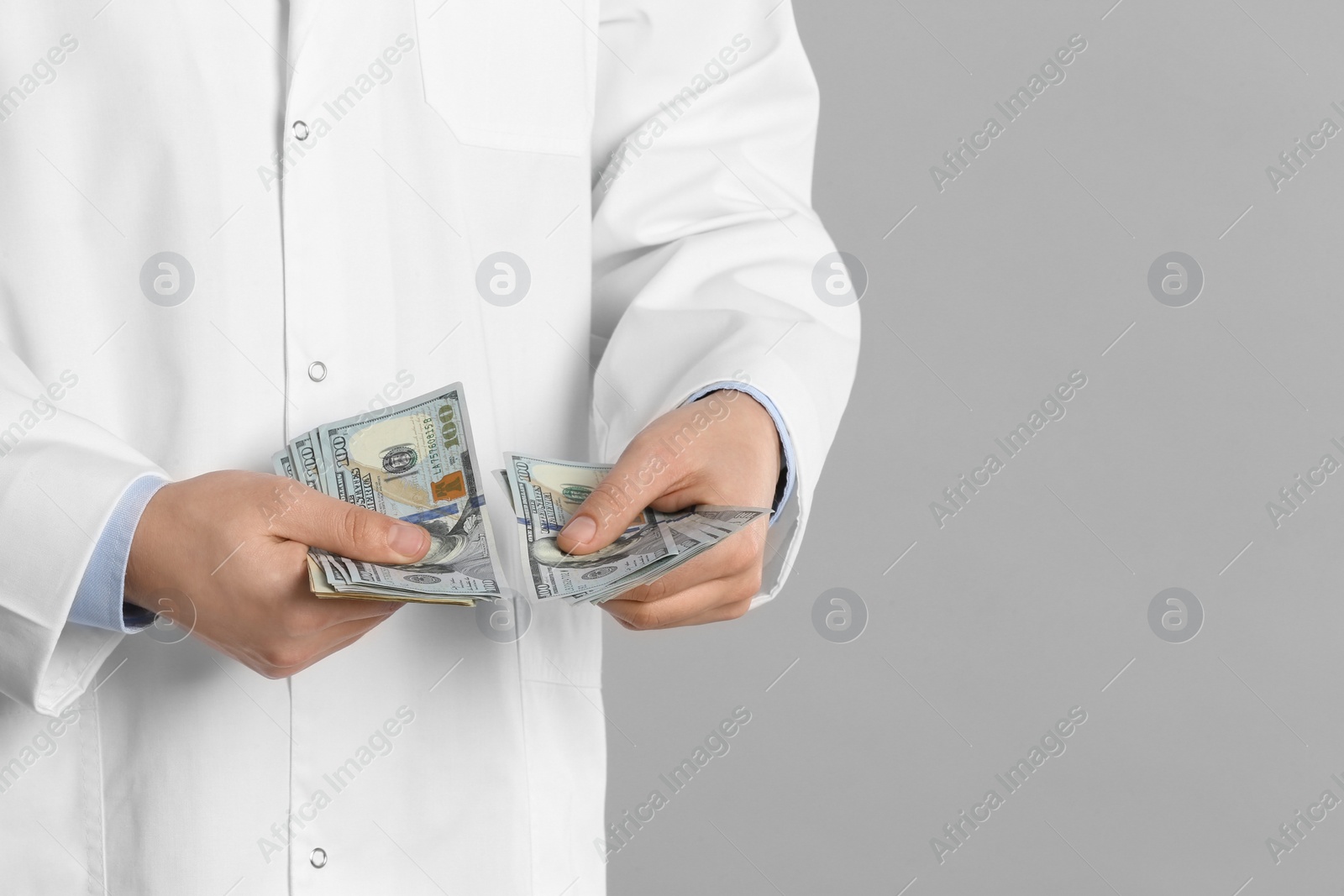 Photo of Doctor with bribe on grey background, closeup. Corruption in medicine