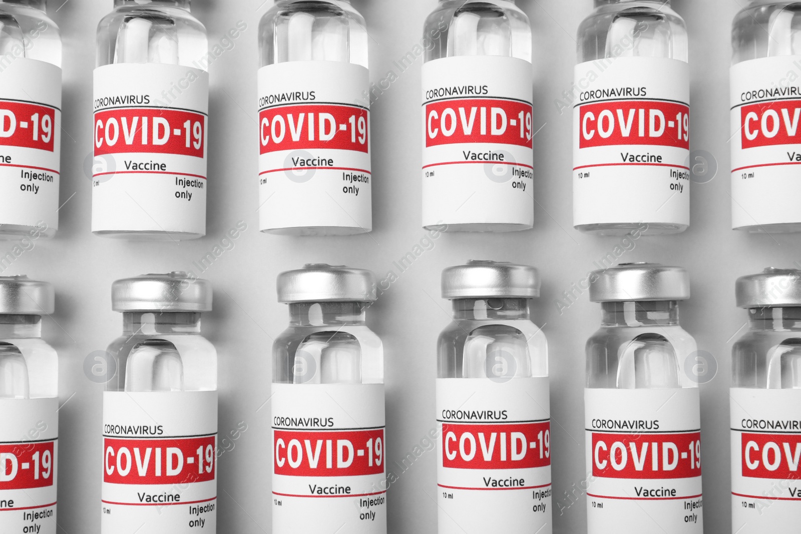 Photo of Glass vials with COVID-19 vaccine on light grey background, flat lay