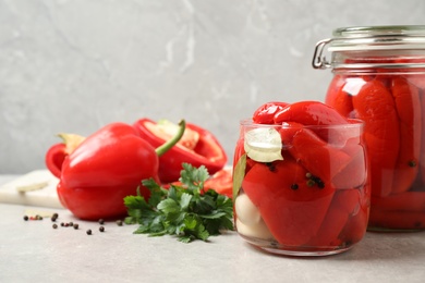 Glass jars with pickled peppers on grey table