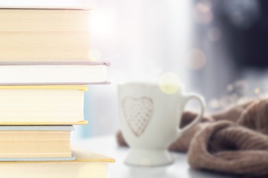 Image of Stack of books and cup on table indoors. Bokeh effect 
