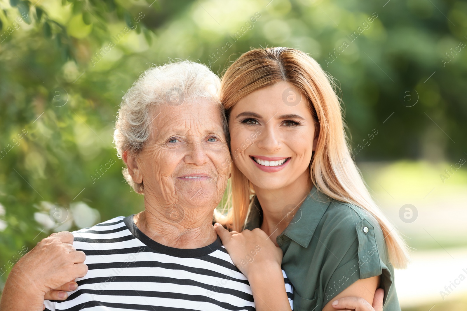 Photo of Woman with elderly mother outdoors on sunny day