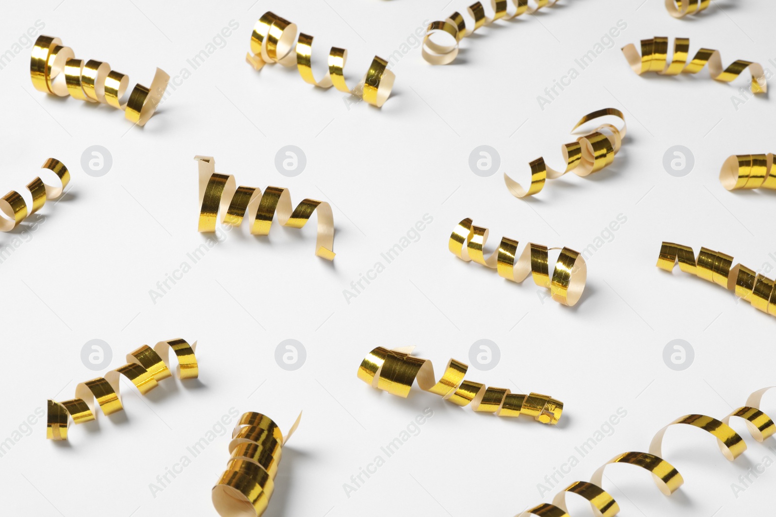 Photo of Shiny golden serpentine streamers on white background