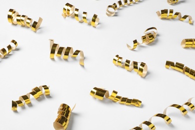 Photo of Shiny golden serpentine streamers on white background