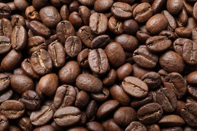 Pile of roasted coffee beans as background, top view