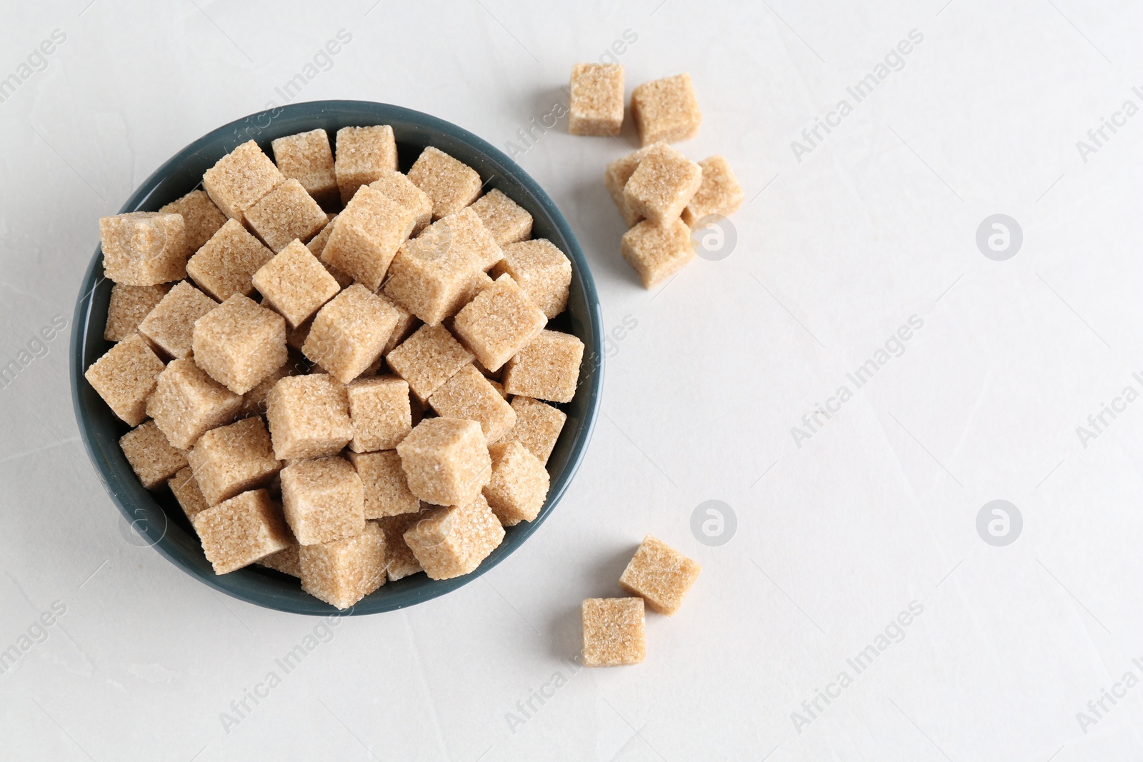 Photo of Brown sugar cubes on white table, flat lay. Space for text