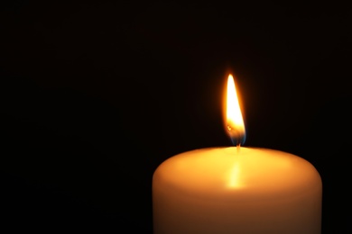 Photo of Burning candle on dark background, closeup with space for text. Symbol of sorrow