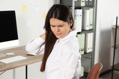 Photo of Young woman suffering from neck pain in office