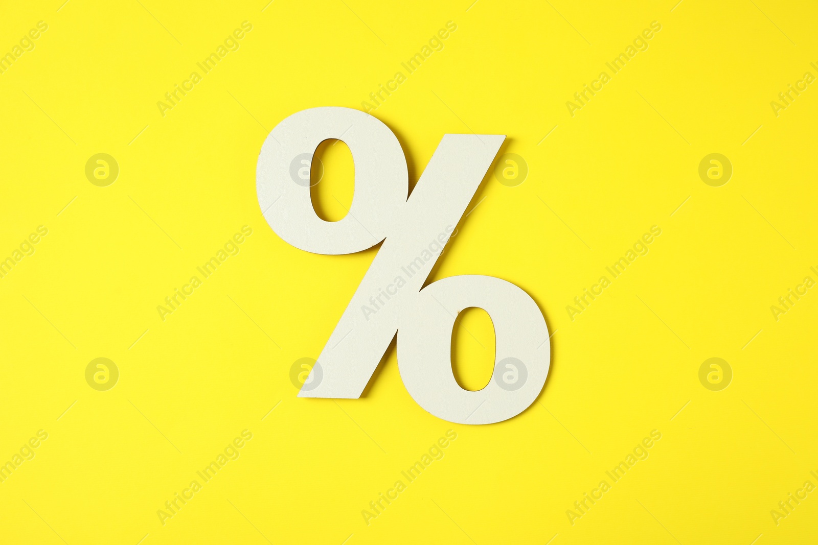 Photo of White percent sign on yellow background, top view