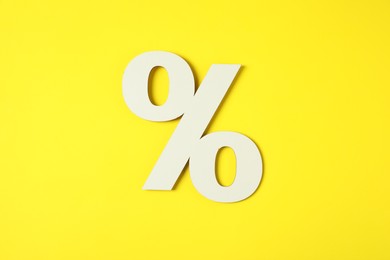 Photo of White percent sign on yellow background, top view