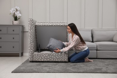 Woman taking pillow from modular sofa section in living room